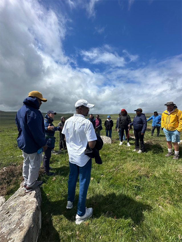 Shows Bristol refugee group at Scorhill stone circle in Devon in June 2026 during visit to Chagford Hospitality Network